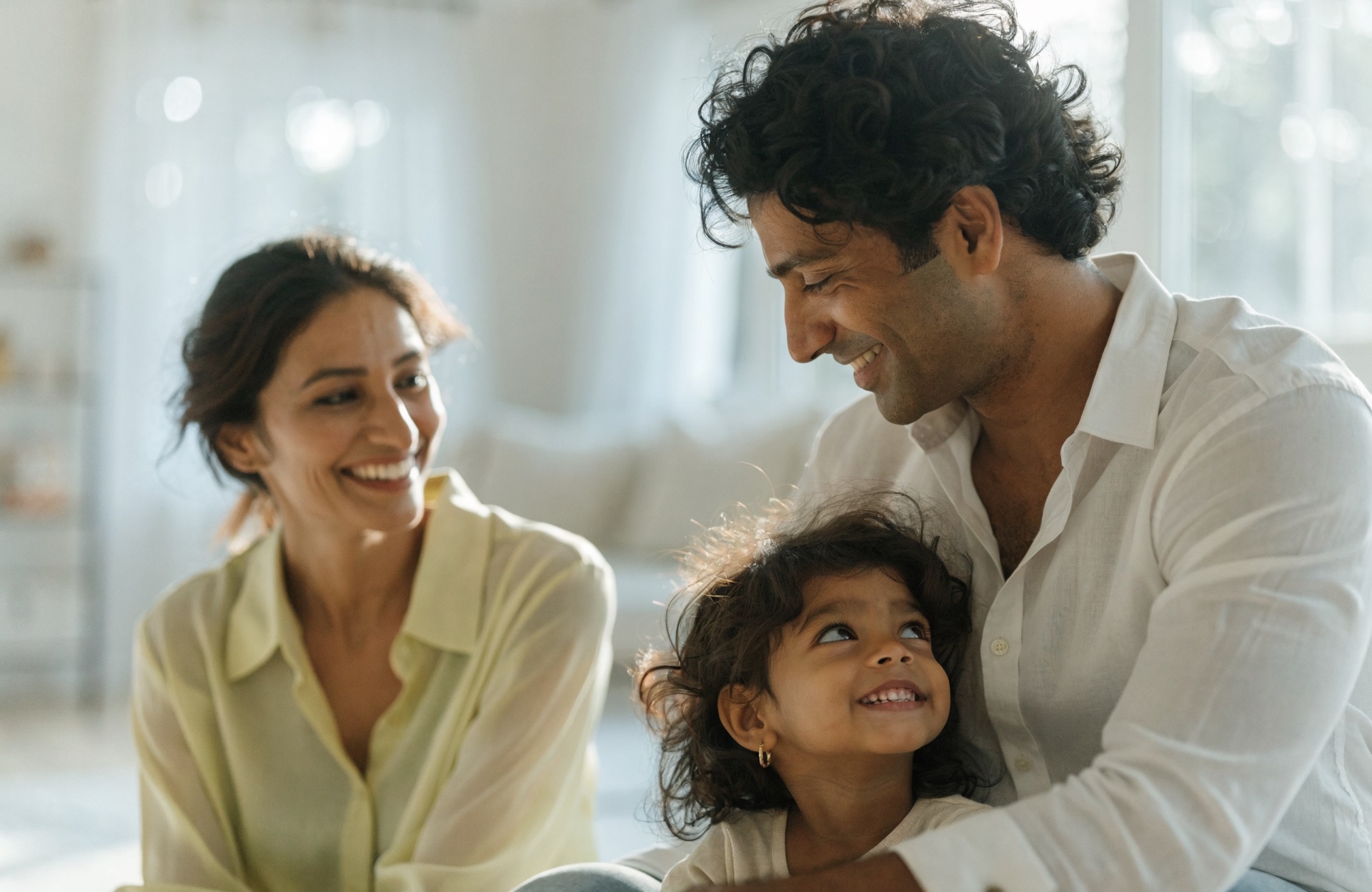 A mother and her child laughing together at home in soft morning light